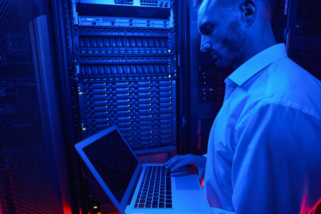 System administrator troubleshooting server rack with laptop