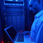 System administrator troubleshooting server rack with laptop