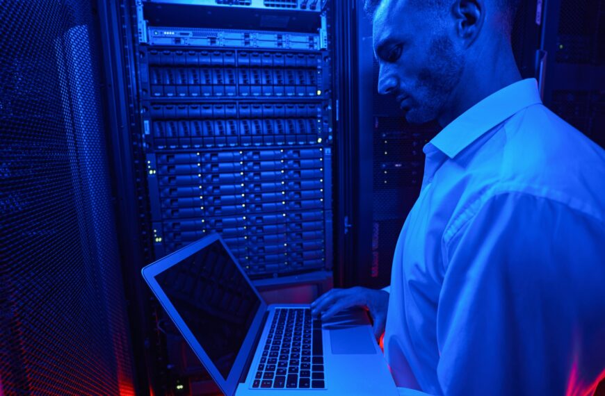 System administrator troubleshooting server rack with laptop