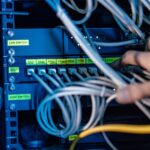 Technician working with ethernet cables and rack-mount switches for Gigabit Ethernet.